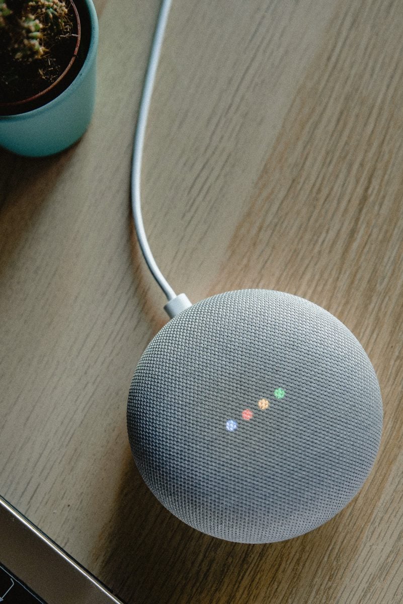 Close up image of a White Google Home device on a wooden table