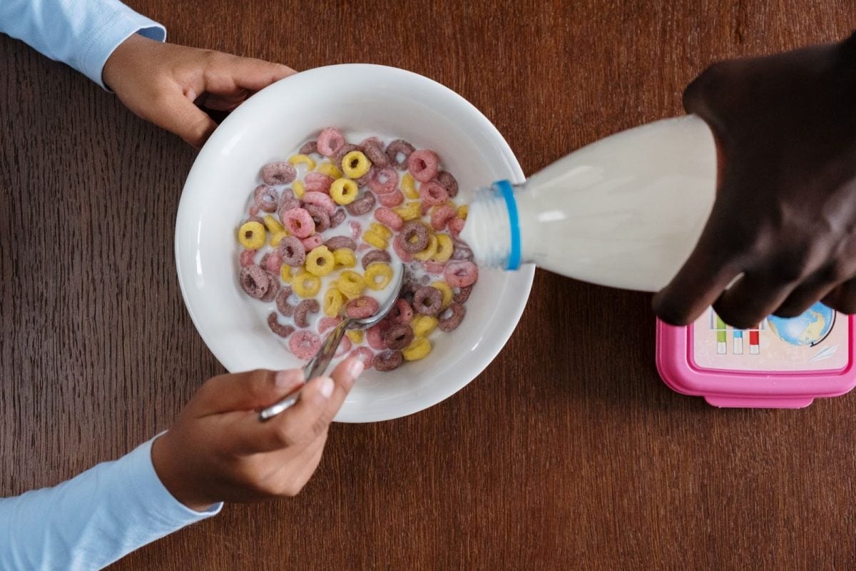 Milk from a bottle being poured into a bowl of cereal
